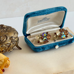Vintage Lisner light smoked topaz and AB topaz gold‑tone floral clip‑on earrings from the 1950s.