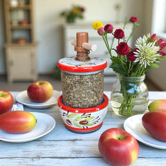Vintage Provence herb mill with hand-painted olive branch motif in green and black on a cream ceramic base, featuring a ridged interior and terracotta accents.