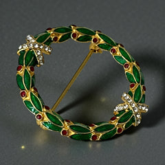 Vintage MMA Fabergé replica Christmas wreath brooch with green guilloché enamel leaves, red berry accents, clear rhinestone ribbon details, and gold‑plated finish; signed MMA © FBS, excellent condition