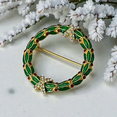 Vintage MMA Fabergé replica Christmas wreath brooch with green guilloché enamel leaves, red berry accents, clear rhinestone ribbon details, and gold‑plated finish; signed MMA © FBS, excellent condition