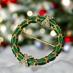 Vintage MMA Fabergé replica Christmas wreath brooch with green guilloché enamel leaves, red berry accents, clear rhinestone ribbon details, and gold‑plated finish; signed MMA © FBS, excellent condition