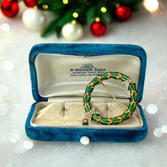 Vintage MMA Fabergé replica Christmas wreath brooch with green guilloché enamel leaves, red berry accents, clear rhinestone ribbon details, and gold‑plated finish; signed MMA © FBS, excellent condition