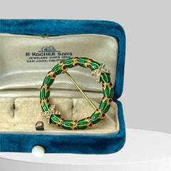 Vintage MMA Fabergé replica Christmas wreath brooch with green guilloché enamel leaves, red berry accents, clear rhinestone ribbon details, and gold‑plated finish; signed MMA © FBS, excellent condition