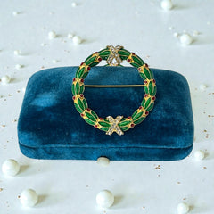 Vintage MMA Fabergé replica Christmas wreath brooch with green guilloché enamel leaves, red berry accents, clear rhinestone ribbon details, and gold‑plated finish; signed MMA © FBS, excellent condition
