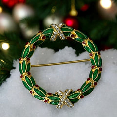 Vintage MMA Fabergé replica Christmas wreath brooch with green guilloché enamel leaves, red berry accents, clear rhinestone ribbon details, and gold‑plated finish; signed MMA © FBS, excellent condition