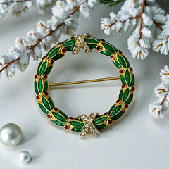 Vintage MMA Fabergé replica Christmas wreath brooch with green guilloché enamel leaves, red berry accents, clear rhinestone ribbon details, and gold‑plated finish; signed MMA © FBS, excellent condition