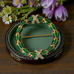 Vintage MMA Fabergé replica Christmas wreath brooch with green guilloché enamel leaves, red berry accents, clear rhinestone ribbon details, and gold‑plated finish; signed MMA © FBS, excellent condition