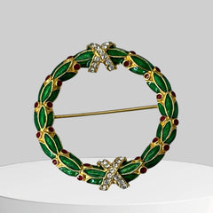Vintage MMA Fabergé replica Christmas wreath brooch with green guilloché enamel leaves, red berry accents, clear rhinestone ribbon details, and gold‑plated finish; signed MMA © FBS, excellent condition