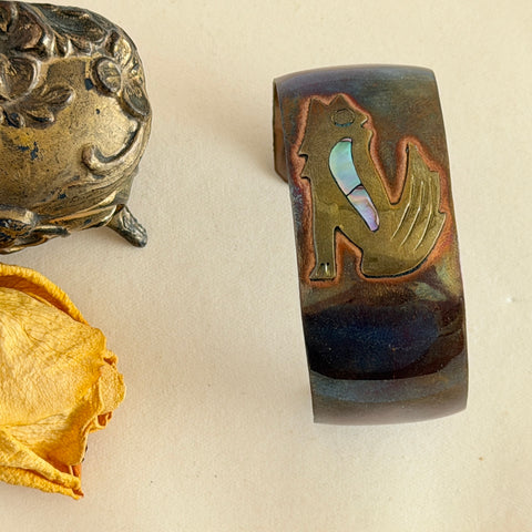 Vintage Southwestern copper and brass cuff bracelet with abalone wolf motif and natural patina, shown from multiple angles.