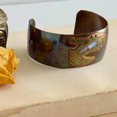 Vintage Southwestern copper and brass cuff bracelet with abalone wolf motif and natural patina, shown from multiple angles.