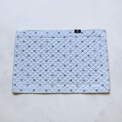 Reversible quilted cotton placemat in Lauris Light Green by Marat d’Avignon, featuring a white center with lavender purple floral medallions and a border of lavender sprigs and olive branches, with a white reverse side  scattered with tiny lavender  blossoms, crafted in Provence.