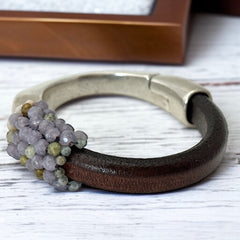 Brown leather and silver-tone half cuff bracelet with magnetic clasp, hand-stitched faceted purple and green amethyst beads, featuring a signature gold accent bead; size 6.