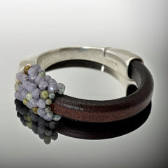 Brown leather and silver-tone half cuff bracelet with magnetic clasp, hand-stitched faceted purple and green amethyst beads, featuring a signature gold accent bead; size 6.