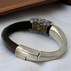 Brown leather and silver-tone half cuff bracelet with magnetic clasp, hand-stitched faceted purple and green amethyst beads, featuring a signature gold accent bead; size 6.
