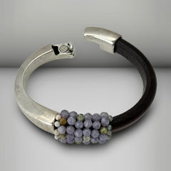 Brown leather and silver-tone half cuff bracelet with magnetic clasp, hand-stitched faceted purple and green amethyst beads, featuring a signature gold accent bead; size 6.