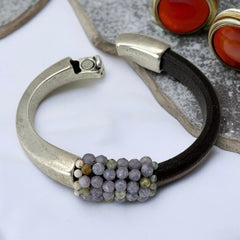 Brown leather and silver-tone half cuff bracelet with magnetic clasp, hand-stitched faceted purple and green amethyst beads, featuring a signature gold accent bead; size 6.