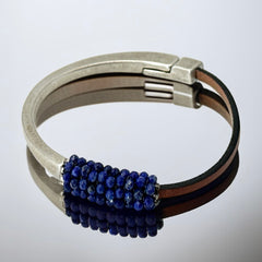 Artisan bracelet featuring a silver-tone half cuff and brown leather band, hand-stitched with faceted lapis beads and a signature gold accent; Martell Studio design, size 6 with magnetic clasp.
