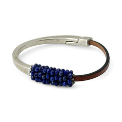 Artisan bracelet featuring a silver-tone half cuff and brown leather band, hand-stitched with faceted lapis beads and a signature gold accent; Martell Studio design, size 6 with magnetic clasp.