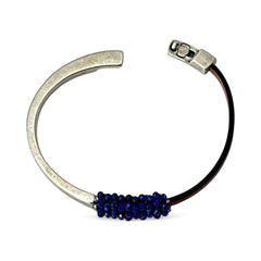 Artisan bracelet featuring a silver-tone half cuff and brown leather band, hand-stitched with faceted lapis beads and a signature gold accent; Martell Studio design, size 6 with magnetic clasp.