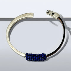 Artisan bracelet featuring a silver-tone half cuff and brown leather band, hand-stitched with faceted lapis beads and a signature gold accent; Martell Studio design, size 6 with magnetic clasp.