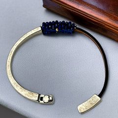 Artisan bracelet featuring a silver-tone half cuff and brown leather band, hand-stitched with faceted lapis beads and a signature gold accent; Martell Studio design, size 6 with magnetic clasp.