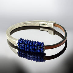 Artisan bracelet featuring a silver-tone half cuff and brown leather band, hand-stitched with faceted lapis beads and a signature gold accent; Martell Studio design, size 6 with magnetic clasp.
