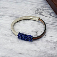 Artisan bracelet featuring a silver-tone half cuff and brown leather band, hand-stitched with faceted lapis beads and a signature gold accent; Martell Studio design, size 6 with magnetic clasp.