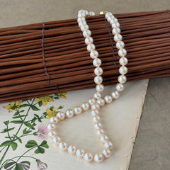 A vintage Marvella cream faux pearl necklace with hand‑knotted pearls and a gold‑tone slide clasp, displayed  with soft natural light highlighting the luster of the pearls.