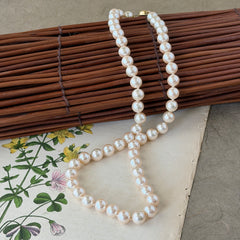 A vintage Marvella cream faux pearl necklace with hand‑knotted pearls and a gold‑tone slide clasp, displayed  with soft natural light highlighting the luster of the pearls.
