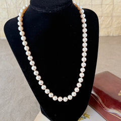 A vintage Marvella cream faux pearl necklace with hand‑knotted pearls and a gold‑tone slide clasp, displayed  with soft natural light highlighting the luster of the pearls.