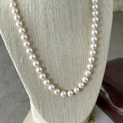 A vintage Marvella cream faux pearl necklace with hand‑knotted pearls and a gold‑tone slide clasp, displayed  with soft natural light highlighting the luster of the pearls.