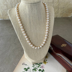 A vintage Marvella cream faux pearl necklace with hand‑knotted pearls and a gold‑tone slide clasp, displayed  with soft natural light highlighting the luster of the pearls.