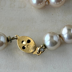 A vintage Marvella cream faux pearl necklace with hand‑knotted pearls and a gold‑tone slide clasp, displayed  with soft natural light highlighting the luster of the pearls.