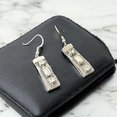 Vintage clear rhinestone and silver tone mesh dangle earrings with emerald-cut rhinestones and chaton accents, paired with sterling silver ear wires, photographed against a clean, neutral backdrop.