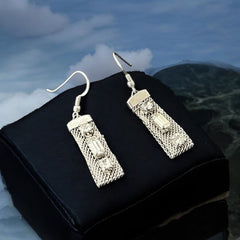 Vintage clear rhinestone and silver tone mesh dangle earrings with emerald-cut rhinestones and chaton accents, paired with sterling silver ear wires, photographed against a clean, neutral backdrop.
