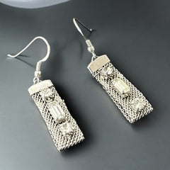 Vintage clear rhinestone and silver tone mesh dangle earrings with emerald-cut rhinestones and chaton accents, paired with sterling silver ear wires, photographed against a clean, neutral backdrop.