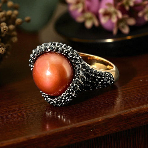 Vintage Honora Italy bronze ring featuring a 12.5mm orange cultured pearl surrounded by faceted black spinel; warm-toned statement jewelry with autumnal elegance and sculptural detail.
