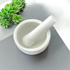 Elegant white porcelain mortar and pestle with glazed exterior and raw interior, designed for tabletop spice grinding and culinary rituals.