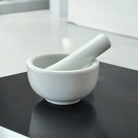 Elegant white porcelain mortar and pestle with glazed exterior and raw interior, designed for tabletop spice grinding and culinary rituals.