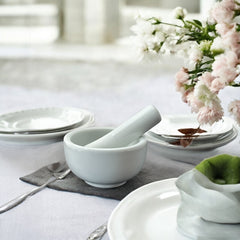 Elegant white porcelain mortar and pestle with glazed exterior and raw interior, designed for tabletop spice grinding and culinary rituals.
