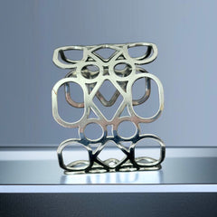 Silver tone cuff bracelet with polished openwork design featuring interconnected ovals, circles, and diamond shapes; modern, unsigned piece with a sleek finish and subtle surface wear.