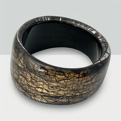 Glossy black and gold Lucite bangle with a freeform silhouette and layered, crackled texture; unsigned and sculptural.