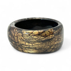 Glossy black and gold Lucite bangle with a freeform silhouette and layered, crackled texture; unsigned and sculptural.