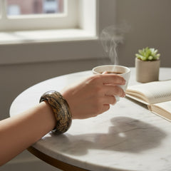 Glossy black and gold Lucite bangle with a freeform silhouette and layered, crackled texture; unsigned and sculptural.