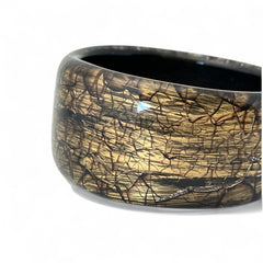 Glossy black and gold Lucite bangle with a freeform silhouette and layered, crackled texture; unsigned and sculptural.