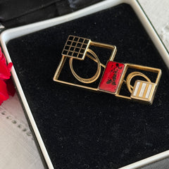 Vintage geometric modernist brooch with red, black, and white enamel in gold‑tone metal.