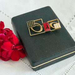Vintage geometric modernist brooch with red, black, and white enamel in gold‑tone metal.