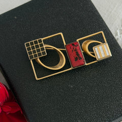Vintage geometric modernist brooch with red, black, and white enamel in gold‑tone metal.