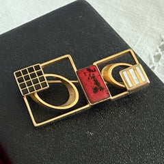 Vintage geometric modernist brooch with red, black, and white enamel in gold‑tone metal.