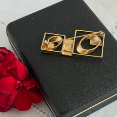 Vintage geometric modernist brooch with red, black, and white enamel in gold‑tone metal.